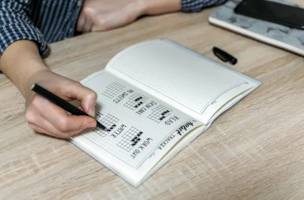 Man marking habits in habit tracker journal.